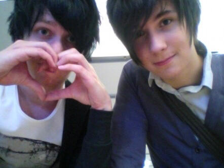 old picture of dan and phil, phil is on the left holding up a hand heart and dan is on the right slightly smiling